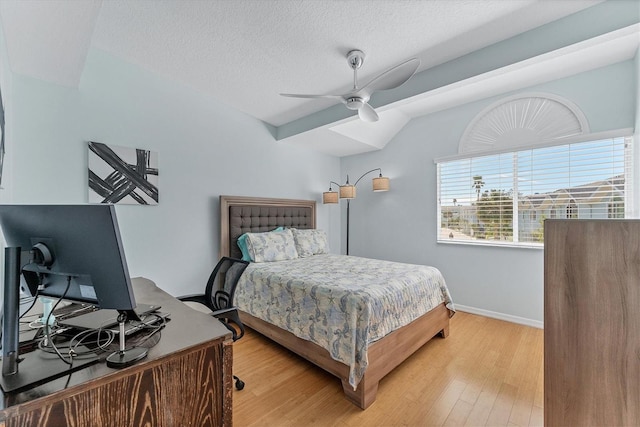 bedroom with a textured ceiling, light hardwood / wood-style flooring, ceiling fan, and vaulted ceiling