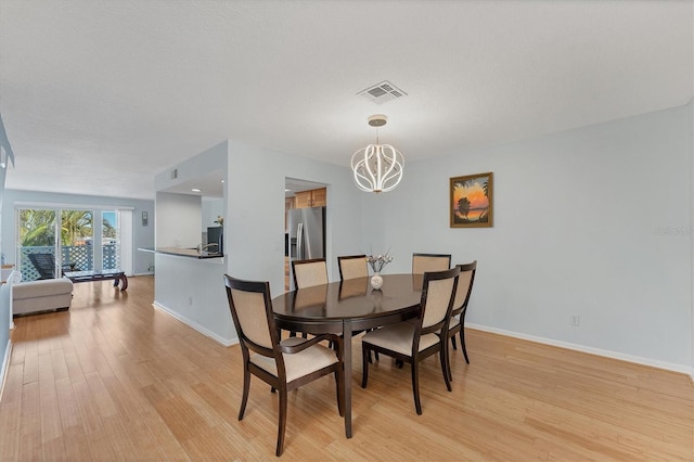 dining space featuring a textured ceiling, light hardwood / wood-style flooring, and a notable chandelier