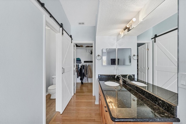 bathroom with hardwood / wood-style floors, vanity, a textured ceiling, and toilet