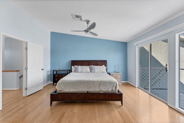 bedroom with light wood-type flooring, a textured ceiling, access to outside, vaulted ceiling, and ceiling fan