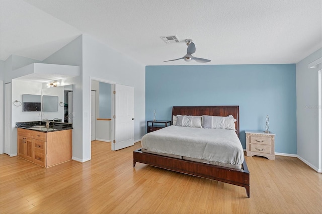 bedroom featuring a towering ceiling, a textured ceiling, light hardwood / wood-style floors, and ceiling fan