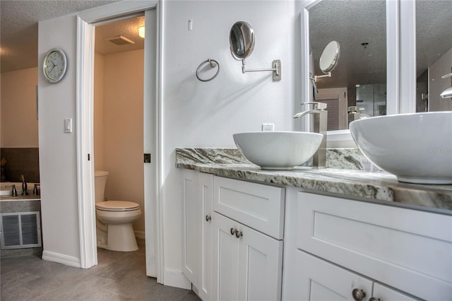 full bath featuring baseboards, visible vents, toilet, a textured ceiling, and vanity