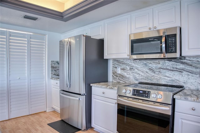 kitchen featuring light wood finished floors, tasteful backsplash, appliances with stainless steel finishes, and white cabinets