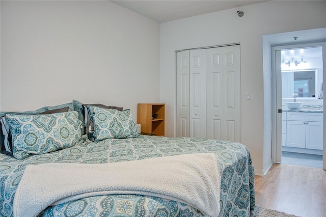 bedroom with a sink, light wood finished floors, connected bathroom, and a closet