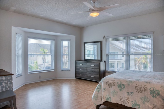 bedroom featuring ceiling fan, light hardwood / wood-style floors, and a textured ceiling