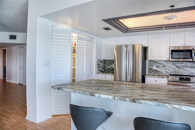 kitchen featuring visible vents, appliances with stainless steel finishes, a textured ceiling, and white cabinetry