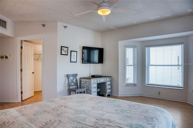 bedroom with visible vents, baseboards, a ceiling fan, a textured ceiling, and light wood-type flooring