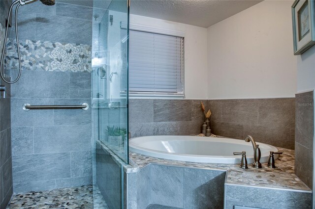 full bath with a textured ceiling, a tile shower, and a bath