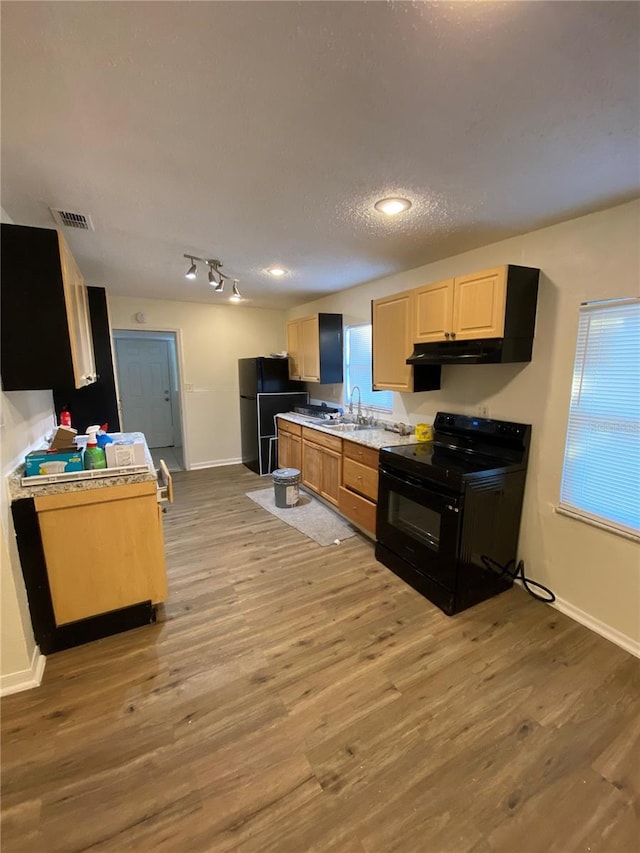 kitchen featuring light brown cabinetry, a textured ceiling, sink, black appliances, and light hardwood / wood-style flooring