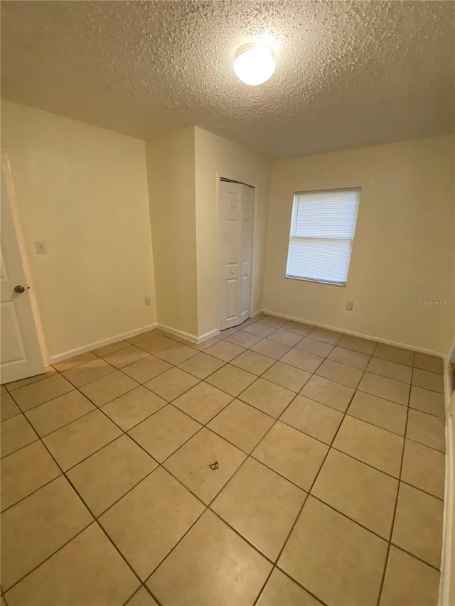 spare room with light tile patterned flooring and a textured ceiling