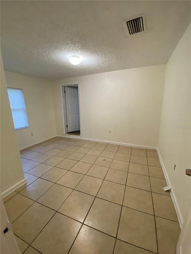 tiled spare room featuring a textured ceiling