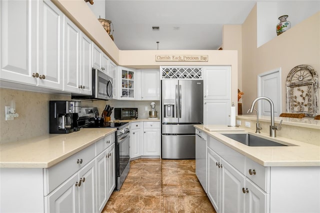 kitchen featuring appliances with stainless steel finishes, backsplash, light stone counters, sink, and white cabinets