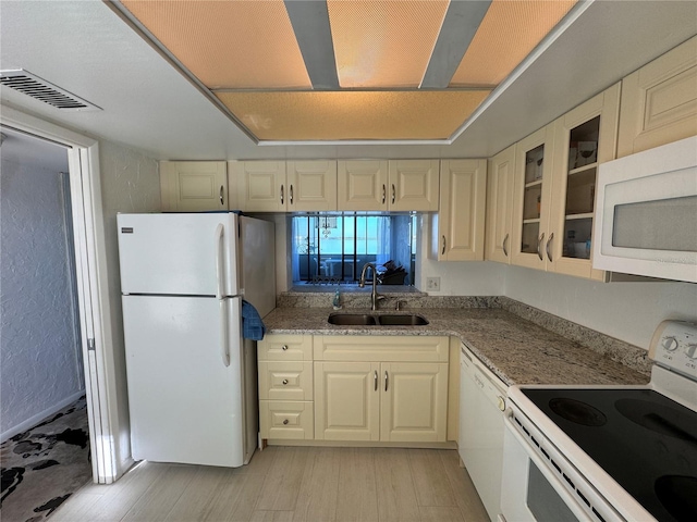 kitchen with cream cabinets, sink, light hardwood / wood-style floors, and white appliances