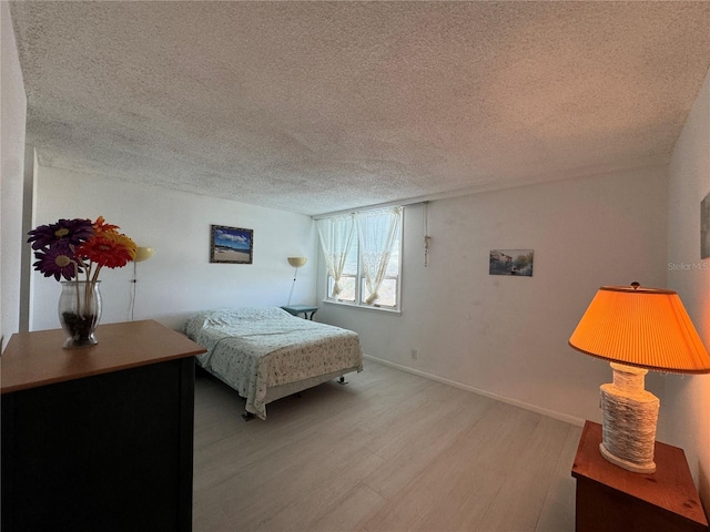 bedroom with a textured ceiling and light hardwood / wood-style flooring