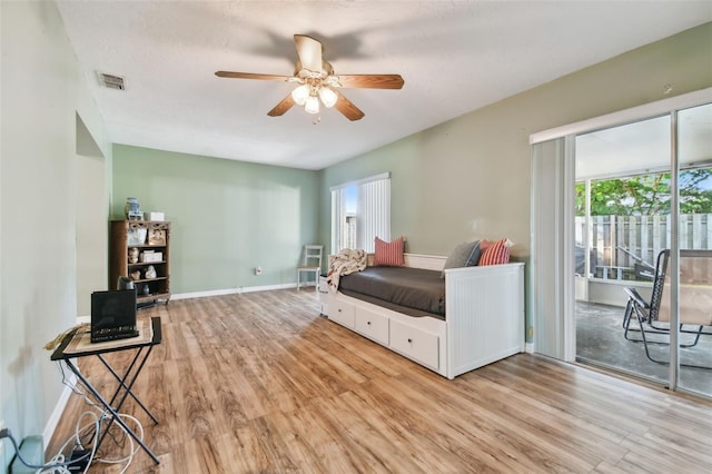 bedroom with access to exterior, a textured ceiling, light hardwood / wood-style flooring, and ceiling fan