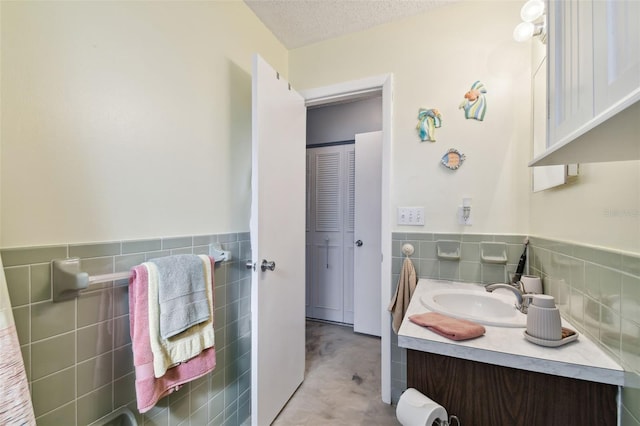 bathroom with vanity, a textured ceiling, and tile walls