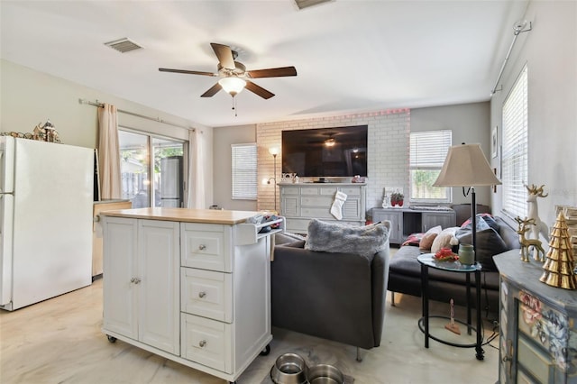 kitchen featuring ceiling fan, white cabinetry, white fridge, and a kitchen island