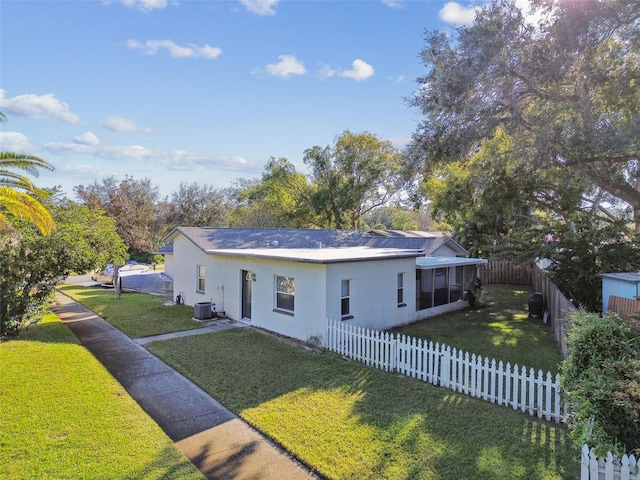 view of front facade featuring a sunroom, a front lawn, and central AC unit