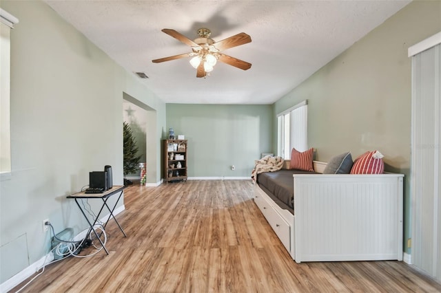 bedroom with a textured ceiling, light hardwood / wood-style flooring, and ceiling fan