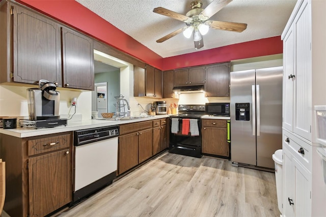 kitchen featuring light wood-type flooring, a textured ceiling, ceiling fan, sink, and black appliances