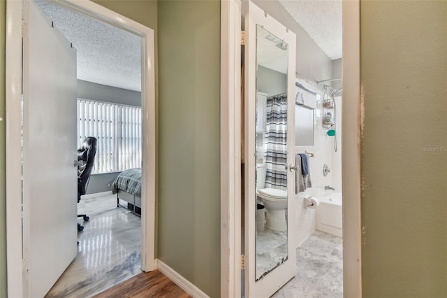 bathroom with hardwood / wood-style floors, a textured ceiling, bathing tub / shower combination, and toilet