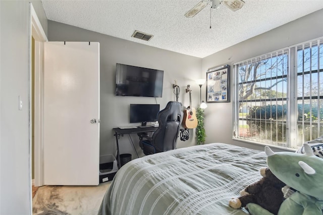 carpeted bedroom with ceiling fan and a textured ceiling