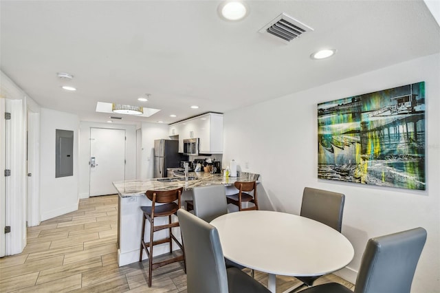 dining space featuring light hardwood / wood-style floors, sink, and electric panel