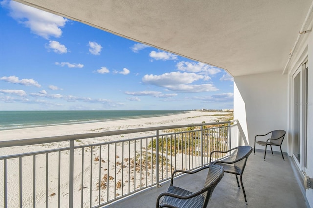 balcony featuring a view of the beach and a water view