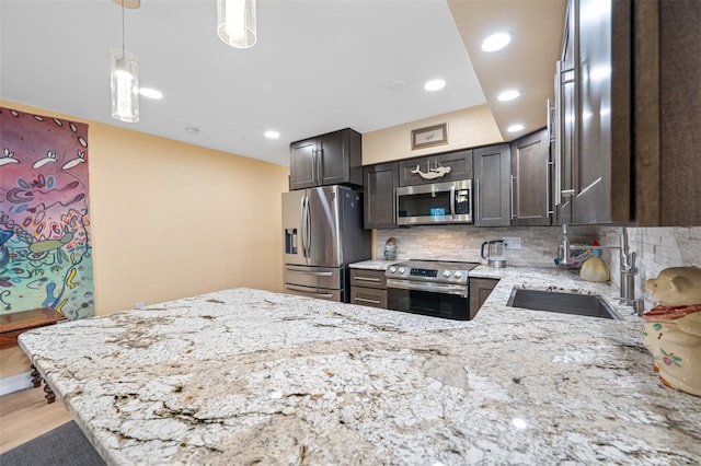 kitchen with pendant lighting, light wood-type flooring, tasteful backsplash, kitchen peninsula, and stainless steel appliances