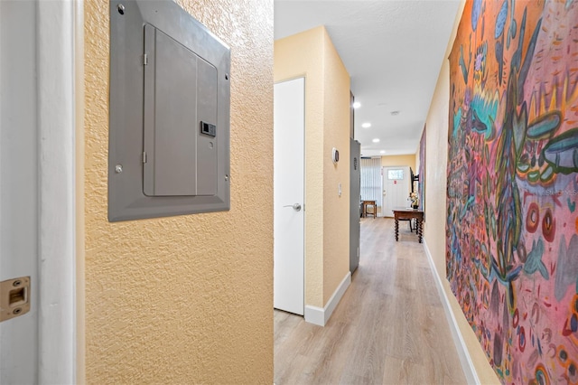 hallway with light hardwood / wood-style floors and electric panel