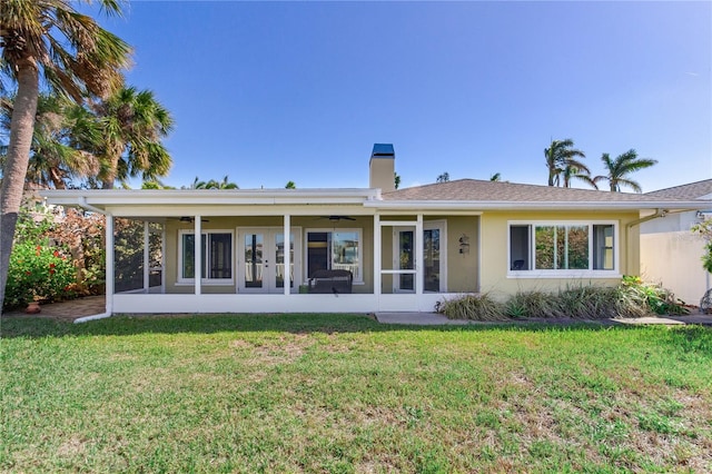 back of property featuring ceiling fan and a yard