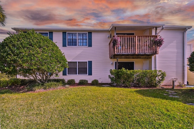 view of front of home with a balcony and a lawn