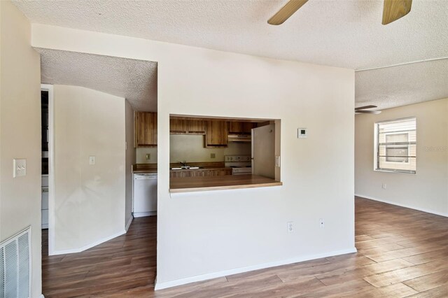 kitchen featuring ceiling fan, range hood, a textured ceiling, white appliances, and hardwood / wood-style flooring