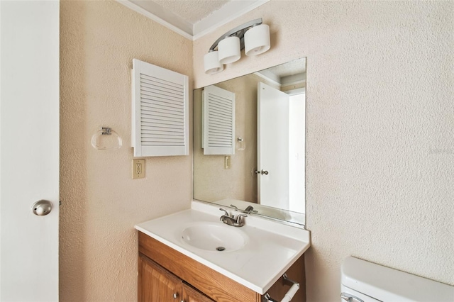 bathroom with a textured ceiling, vanity, toilet, and ornamental molding