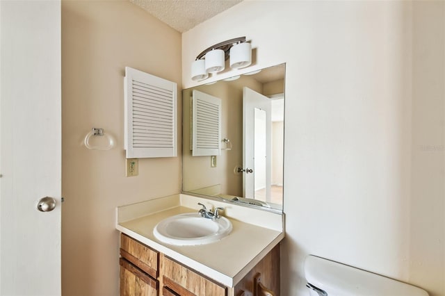 bathroom with vanity, toilet, and a textured ceiling