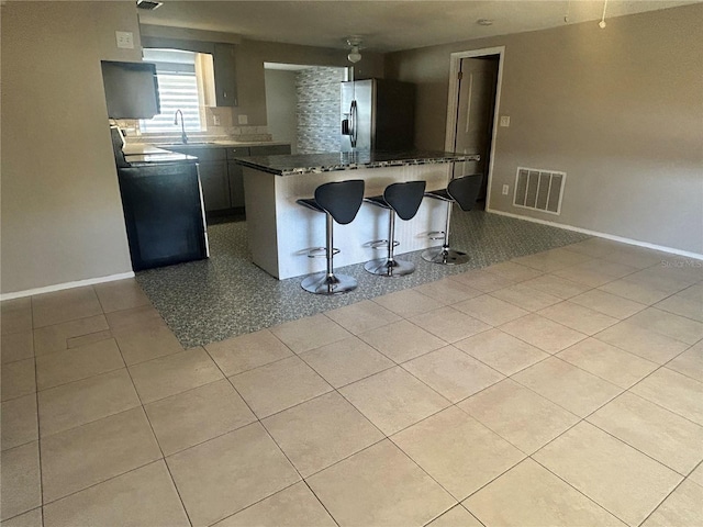 kitchen with sink, stainless steel fridge with ice dispenser, kitchen peninsula, stove, and a kitchen bar