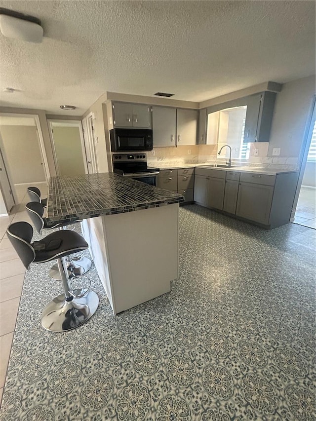 kitchen featuring gray cabinetry, sink, stainless steel electric range oven, and a textured ceiling