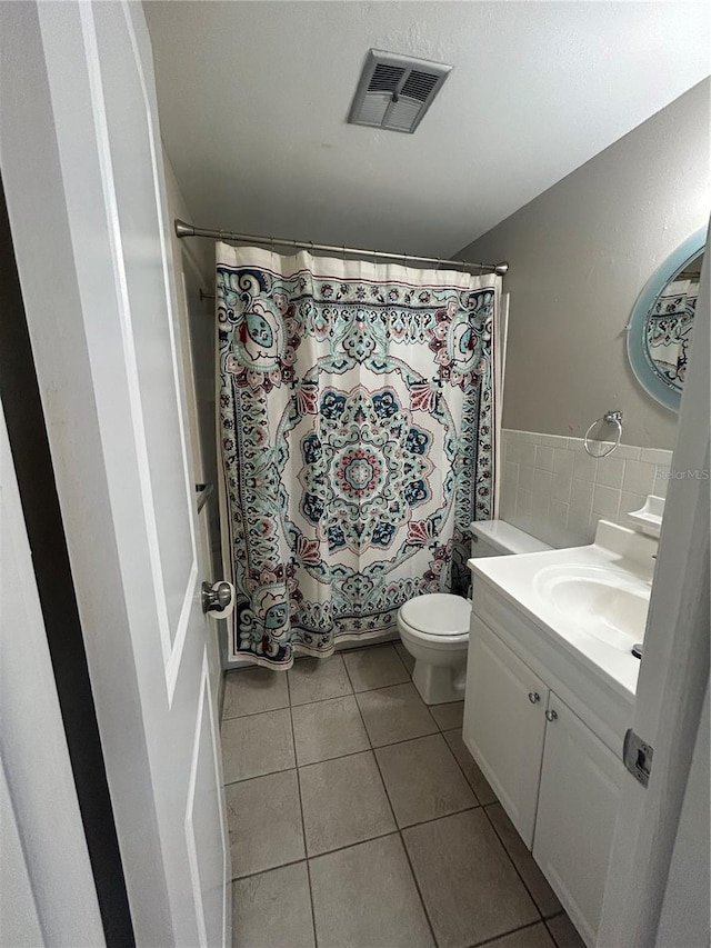 bathroom with toilet, vanity, and tile patterned floors