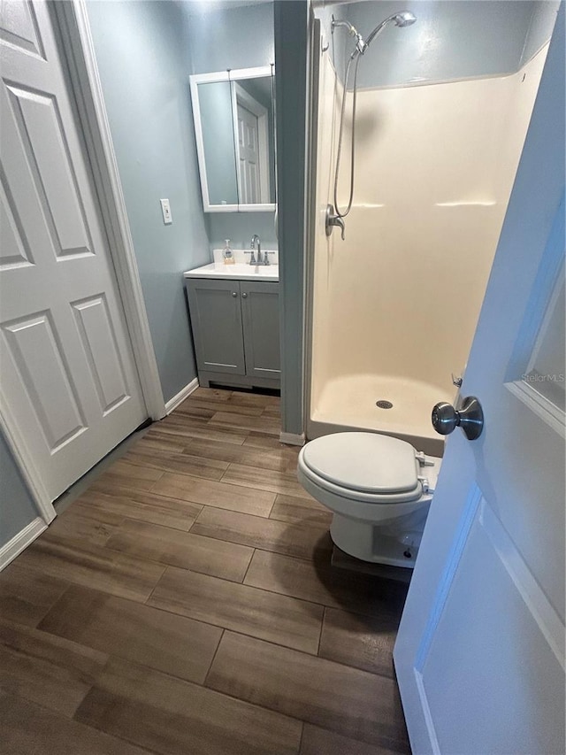 bathroom featuring a shower, hardwood / wood-style floors, vanity, and toilet