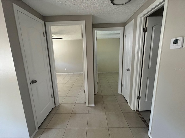 corridor with light tile patterned floors and a textured ceiling