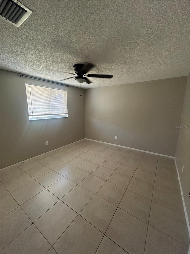 unfurnished room featuring ceiling fan, light tile patterned floors, and a textured ceiling