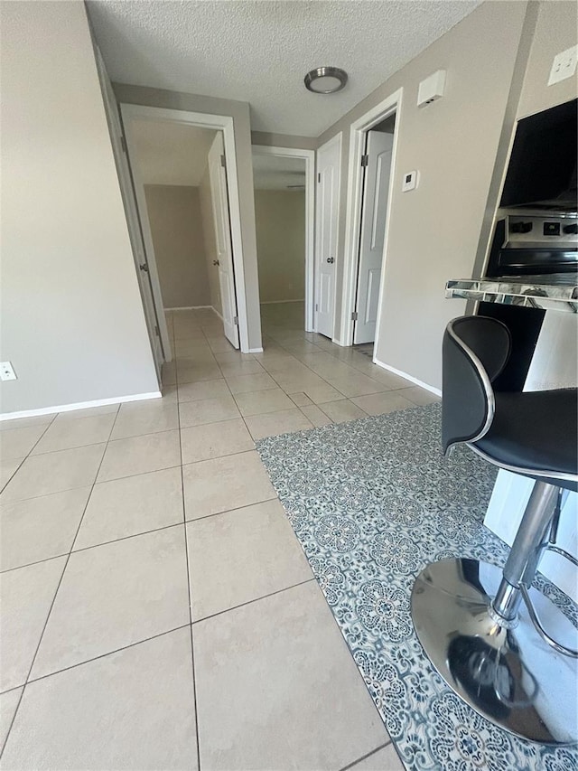 interior space with light tile patterned flooring, a textured ceiling, and stainless steel range