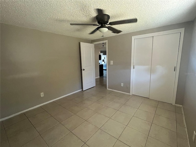 unfurnished bedroom featuring ceiling fan, a closet, light tile patterned floors, and a textured ceiling