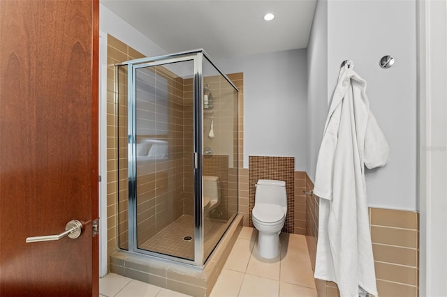 bathroom featuring tile patterned floors, toilet, tile walls, and walk in shower