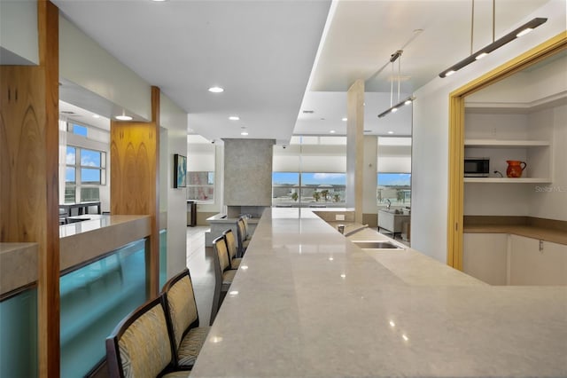 kitchen featuring light stone counters, sink, a healthy amount of sunlight, and decorative light fixtures