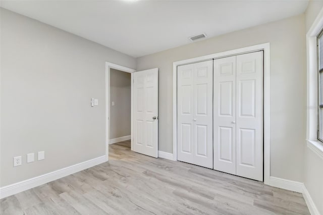 unfurnished bedroom featuring light wood-type flooring and a closet