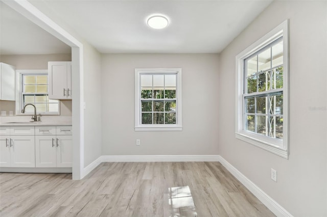 unfurnished dining area featuring light wood-type flooring and sink