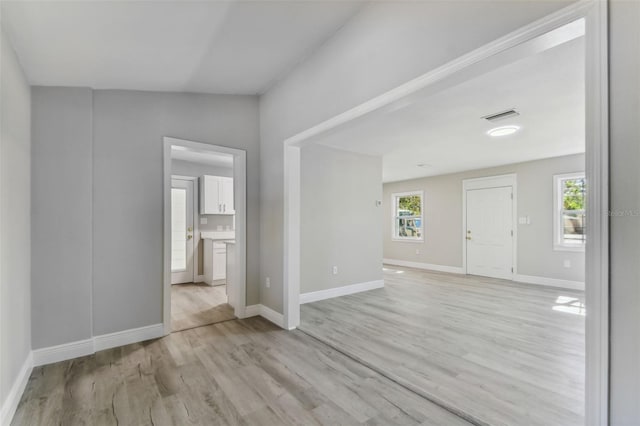 unfurnished room with vaulted ceiling, light hardwood / wood-style flooring, and a wealth of natural light