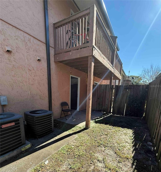 view of property exterior featuring a patio area, a balcony, central air condition unit, and a yard