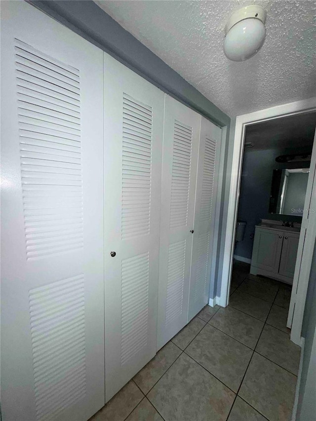 hallway with light tile patterned flooring and a textured ceiling